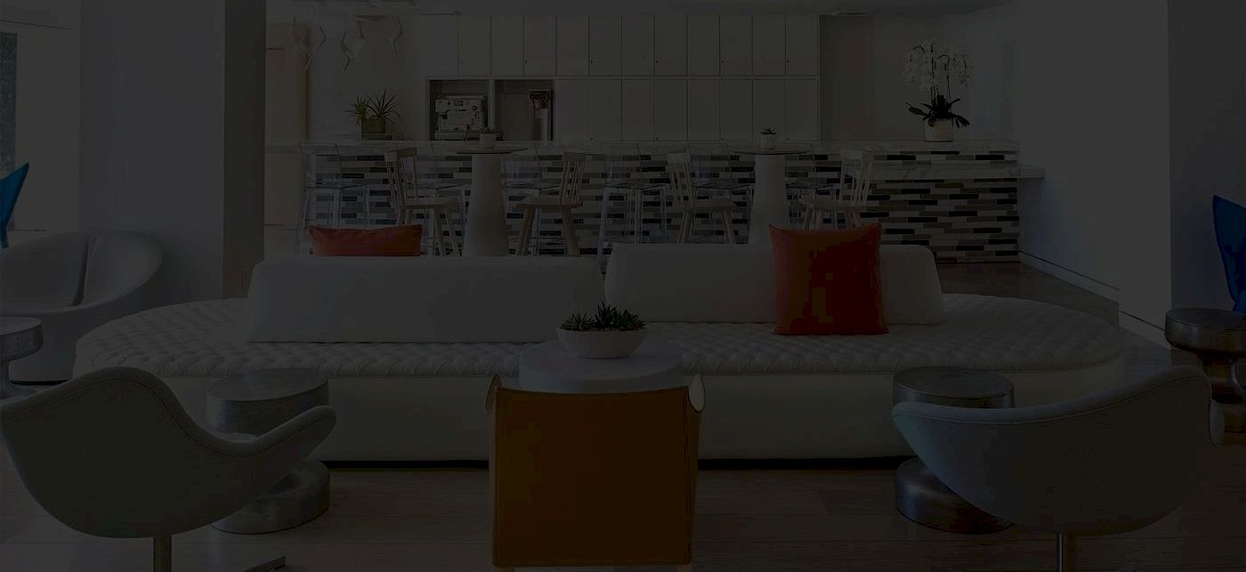 A bright, modern living room with a large white sofa, colorful cushions, futuristic chairs, and a bookshelf/backlit wall in the background, cozy and stylish.